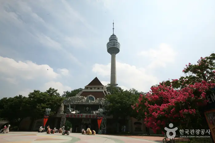 Daegu 83 Tower rising above trees and European-style buildings inside E-World in daylight