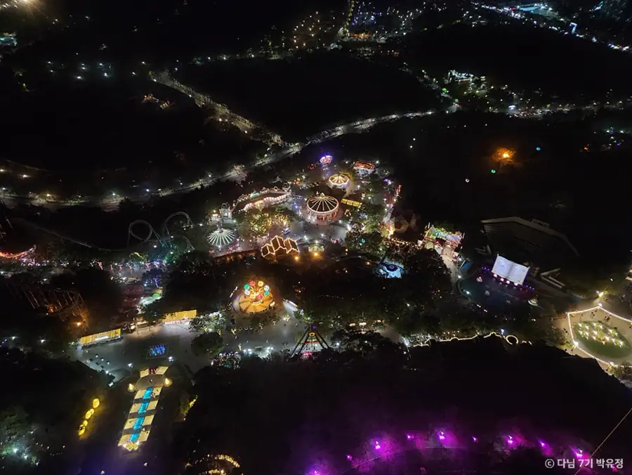 Aerial night view of illuminated rides, pools, paths, and attractions inside Daegu E-World