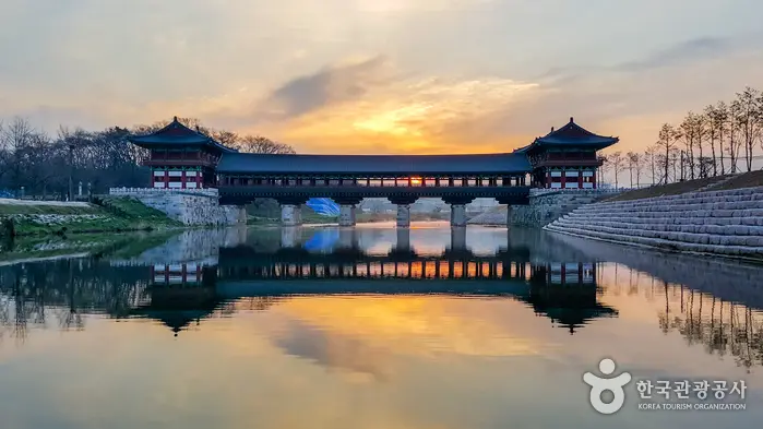黃昏暖色天空下的慶州月精橋與南川水面倒影