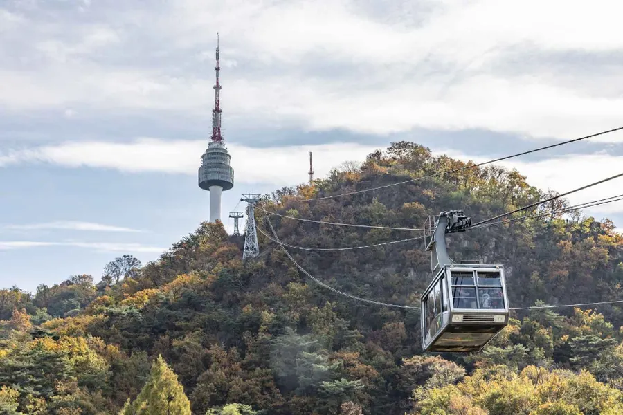 南山樹林上行駛的南山纜車與遠處N Seoul Tower